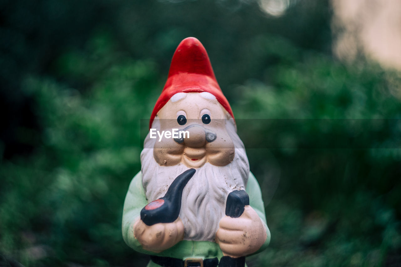 Close-up of garden gnome figurine against christmas tree