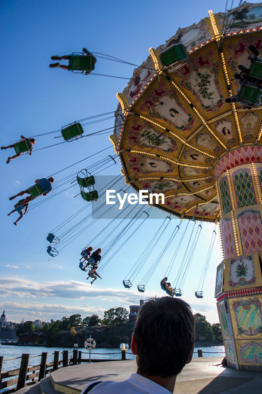 Low angle view of people on amusement park ride against sky