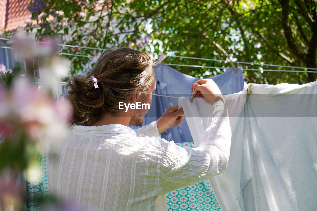 Rear view of young man drying cloths outdoor