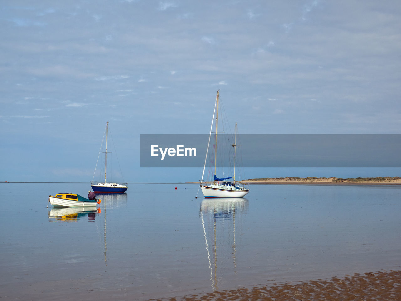 Sailboats moored on sea against sky