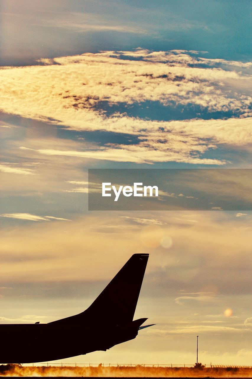 Airplane wing against sky during sunset