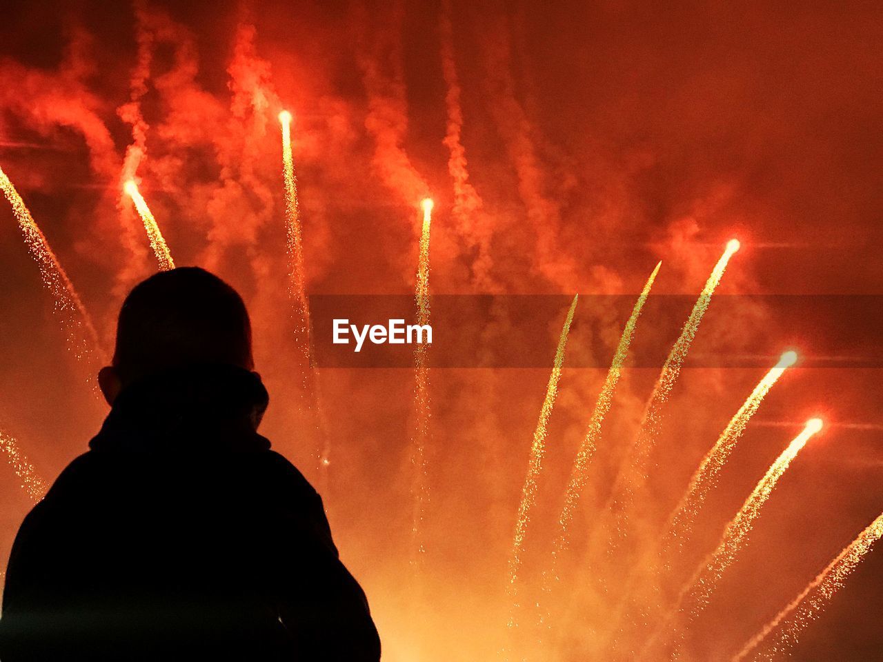 Silhouette person looking at firework display at night