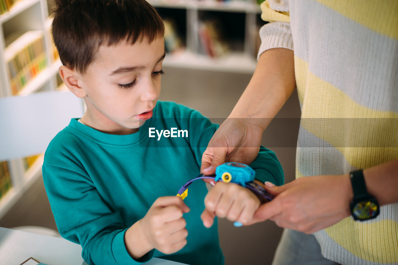 Mom gives her son his first watch. learning to determine the time by the clock.