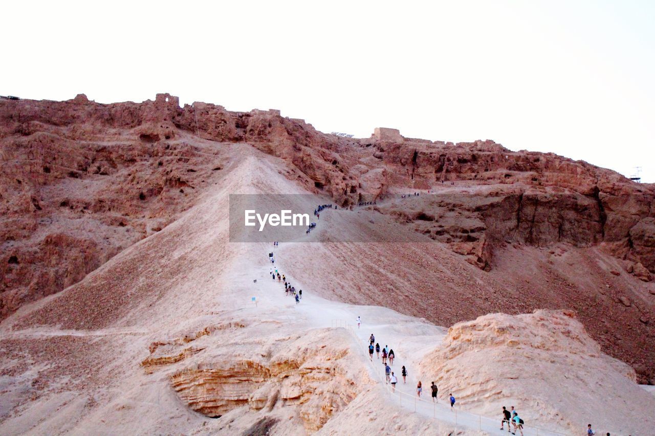 High angle view of people hiking on mountain against clear sky