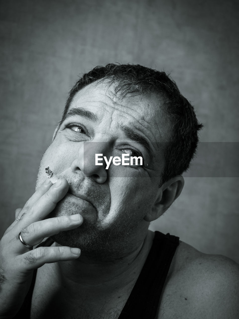 Close-up of man smoking cigarette against wall