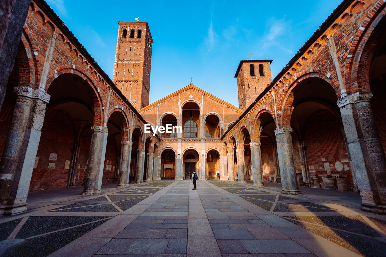 Wide view of the basilica of sant'ambrogio with a tourist in the center of the courtyard