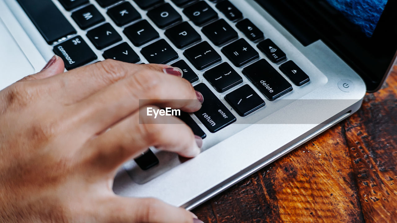 Cropped hand of woman using laptop