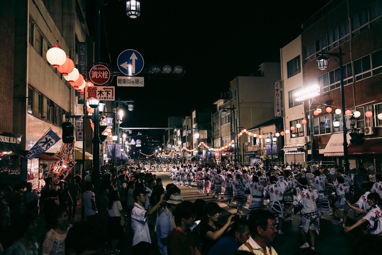 People celebrating awa odori festival on street at night