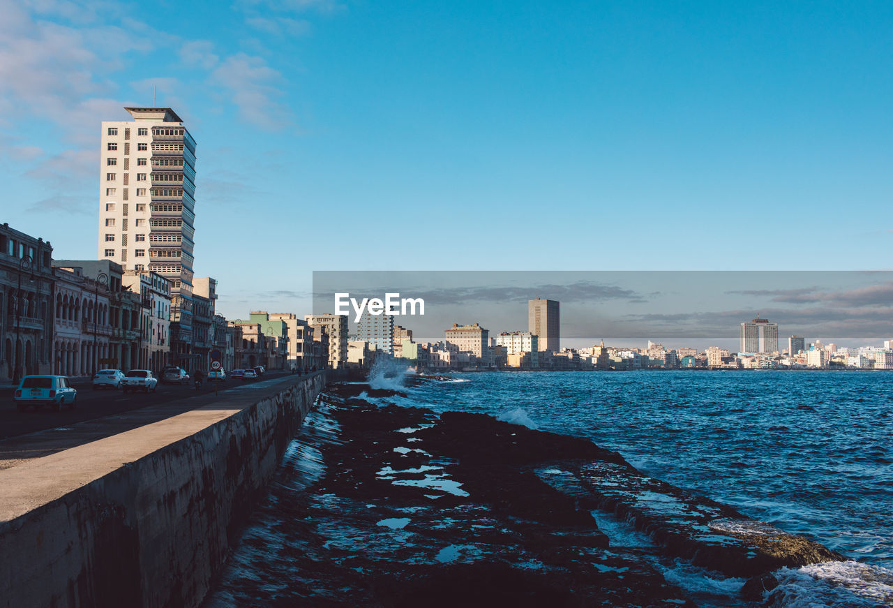 City buildings by sea against sky