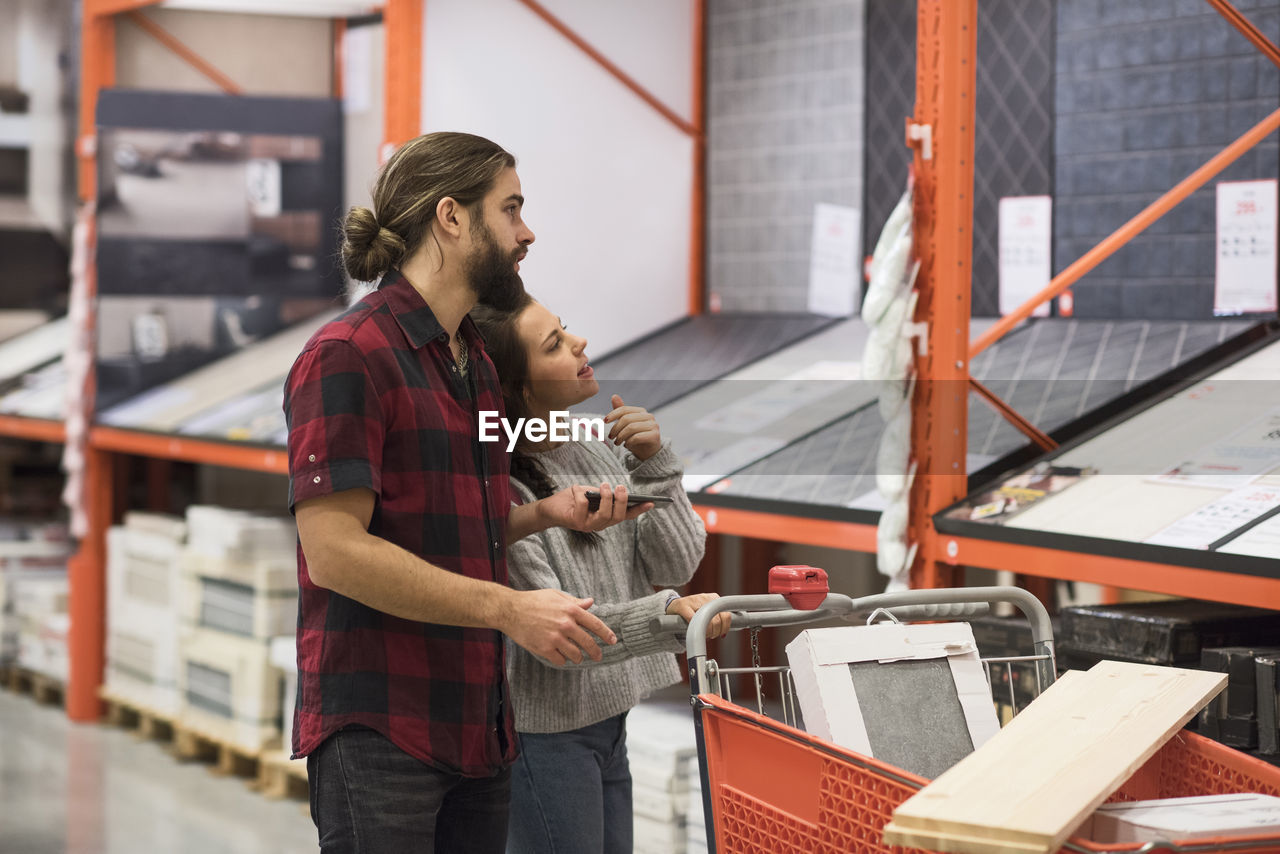 Couple discussing over tiles at hardware store