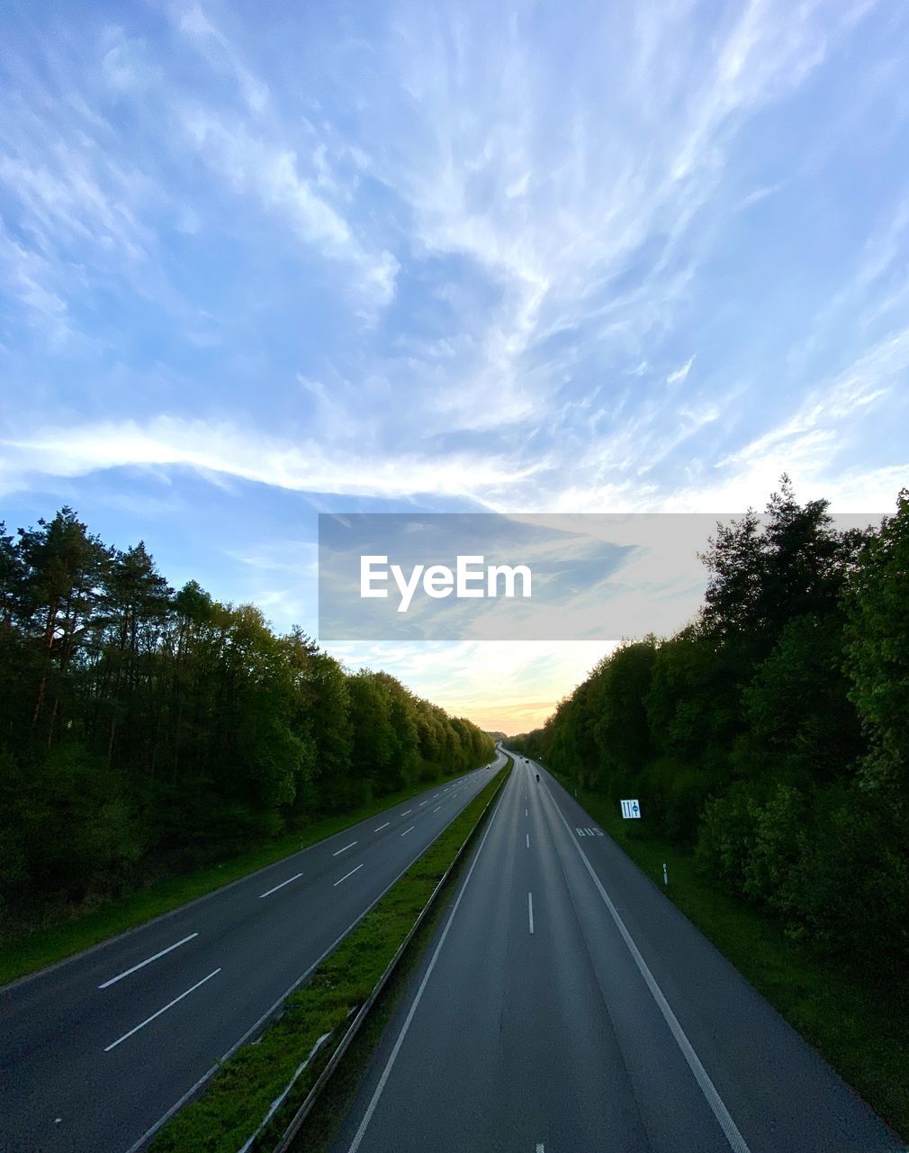 Road passing through trees against sky