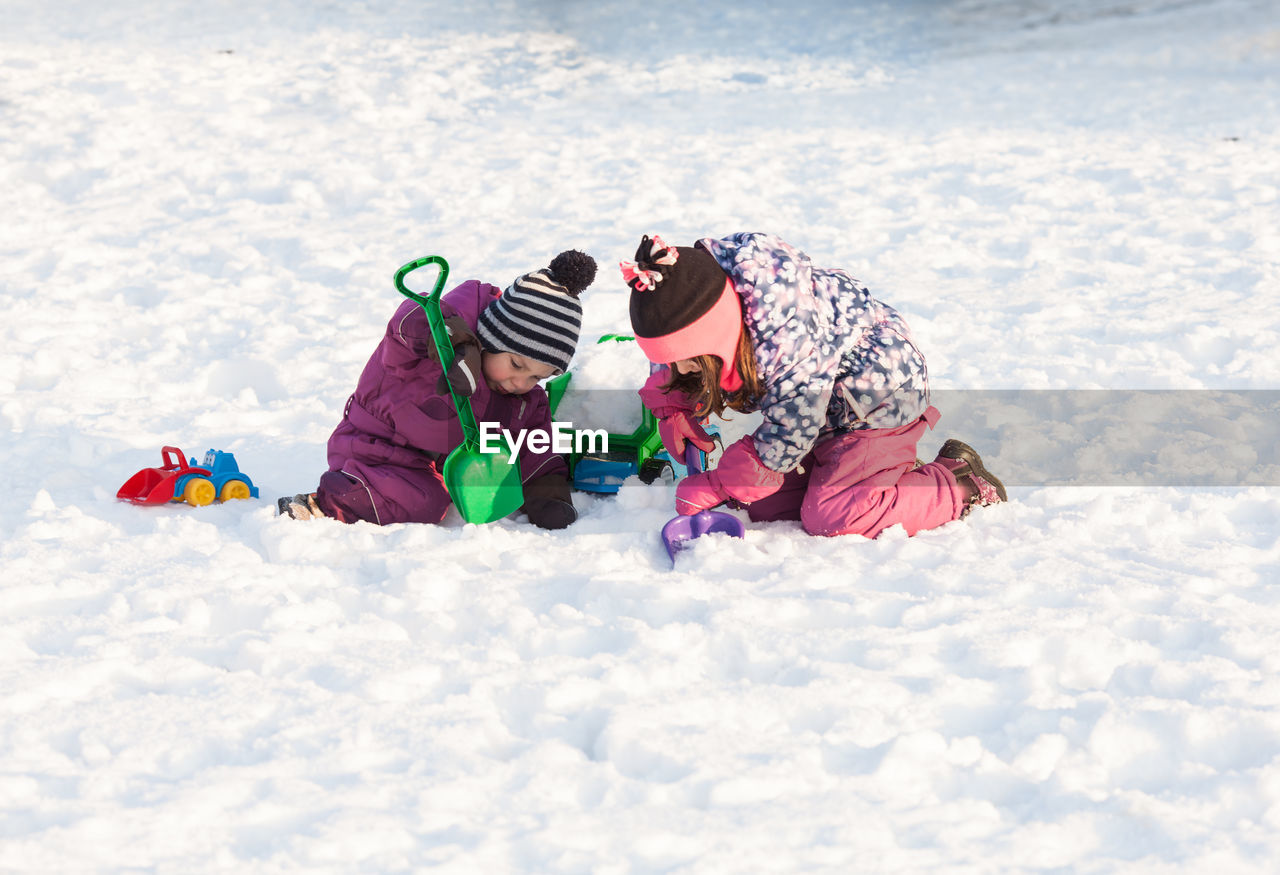 CHILDREN PLAYING ON SNOW COVERED LANDSCAPE