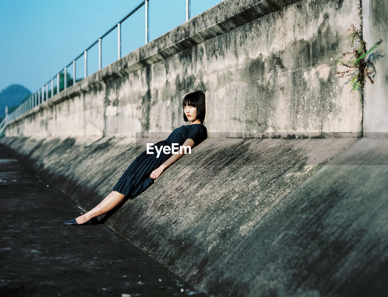 Full length of young woman leaning on wall