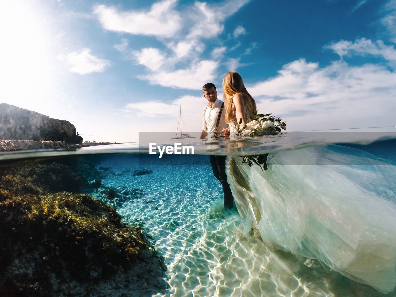 Wedding couple standing in sea against sky