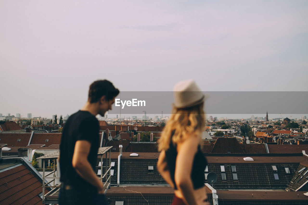 Friends walking on terrace by cityscape against sky