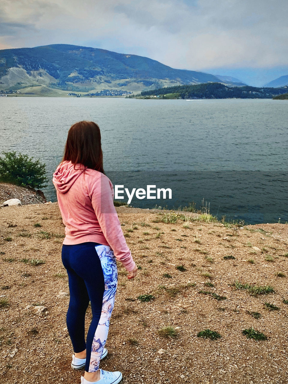 one person, water, rear view, mountain, women, sea, nature, full length, scenics - nature, leisure activity, beauty in nature, land, adult, sky, lifestyles, casual clothing, tranquility, beach, vacation, tranquil scene, landscape, environment, day, hairstyle, shore, female, mountain range, relaxation, trip, non-urban scene, outdoors, holiday, cloud, blue, long hair, standing, walking, sunlight, young adult, solitude, clothing, brown hair, child