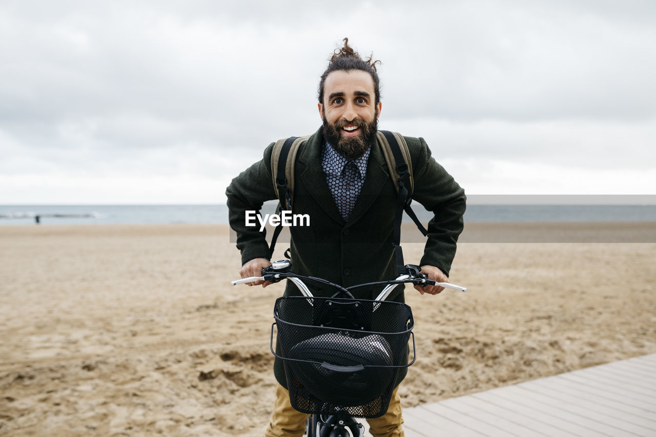 Portrait of happy man with e-bike at the beach