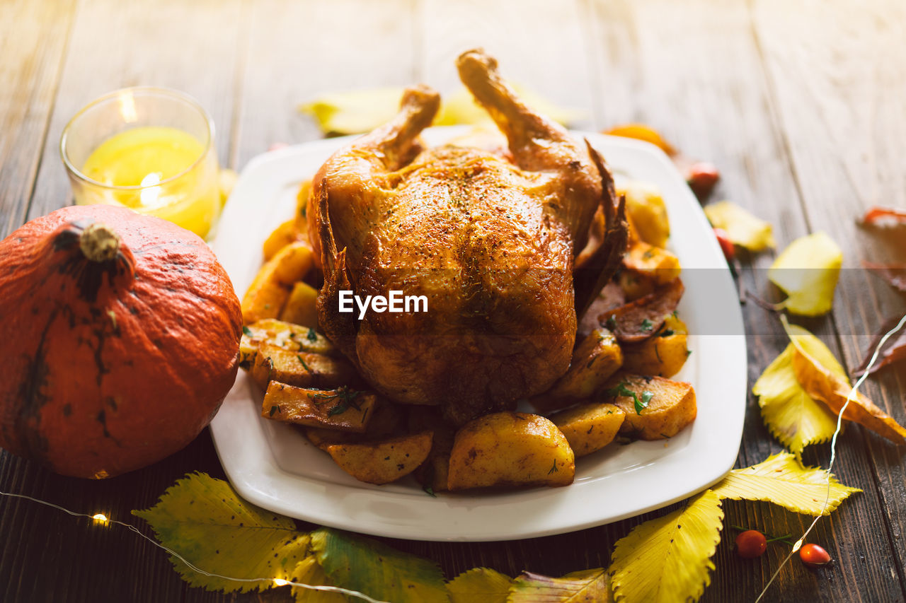 Autumn composition with leaves, ripe pumpkin and thanksgiving turkey on a dark wooden table.
