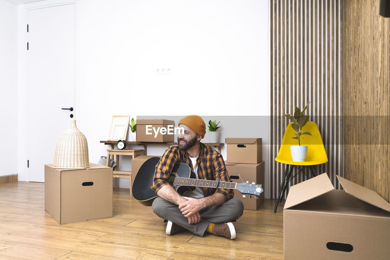 Mature man unpacking things from boxes while moving in new apartment.