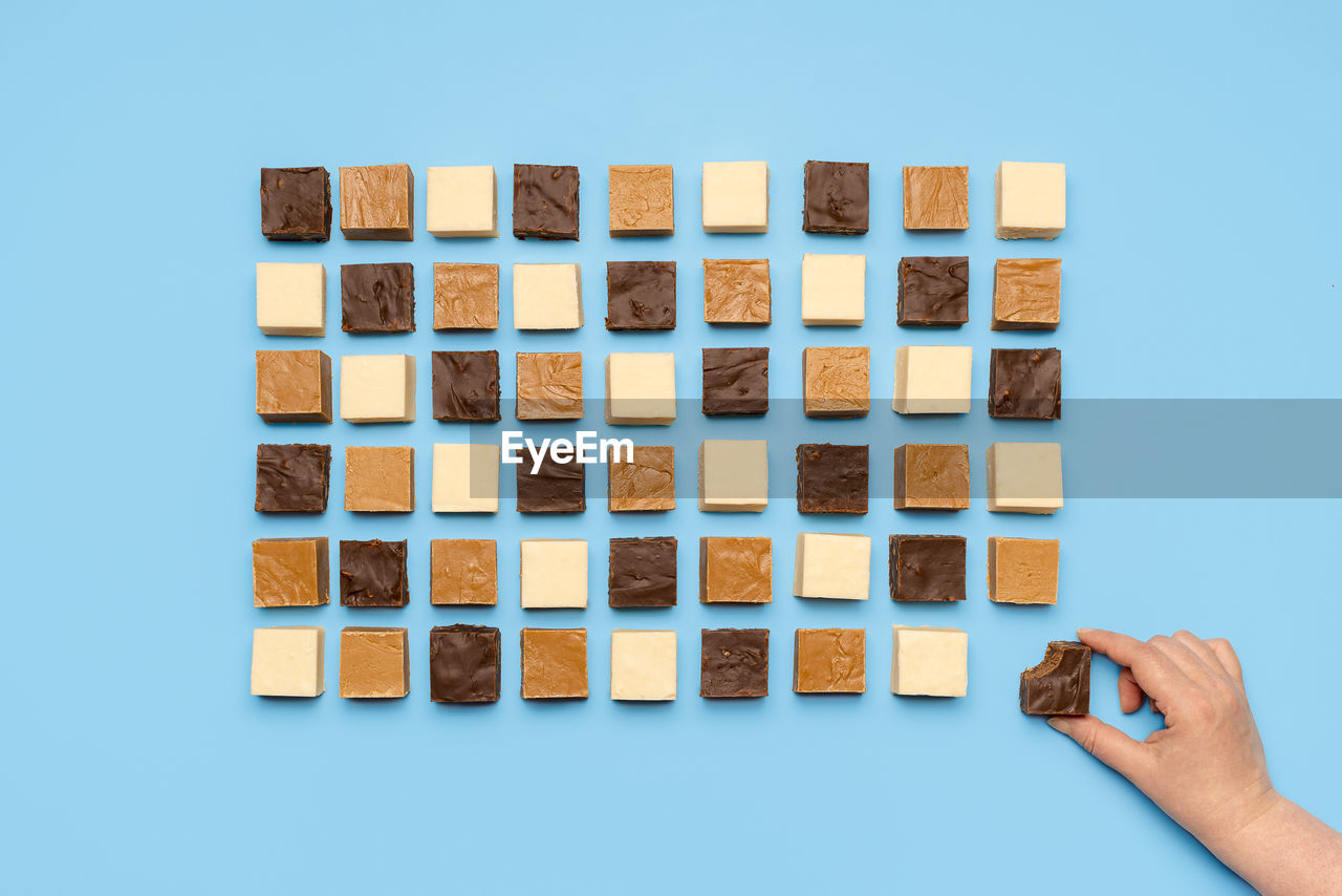 Eating homemade fudge with chocolate, caramel and white chocolate, isolated on blue background.
