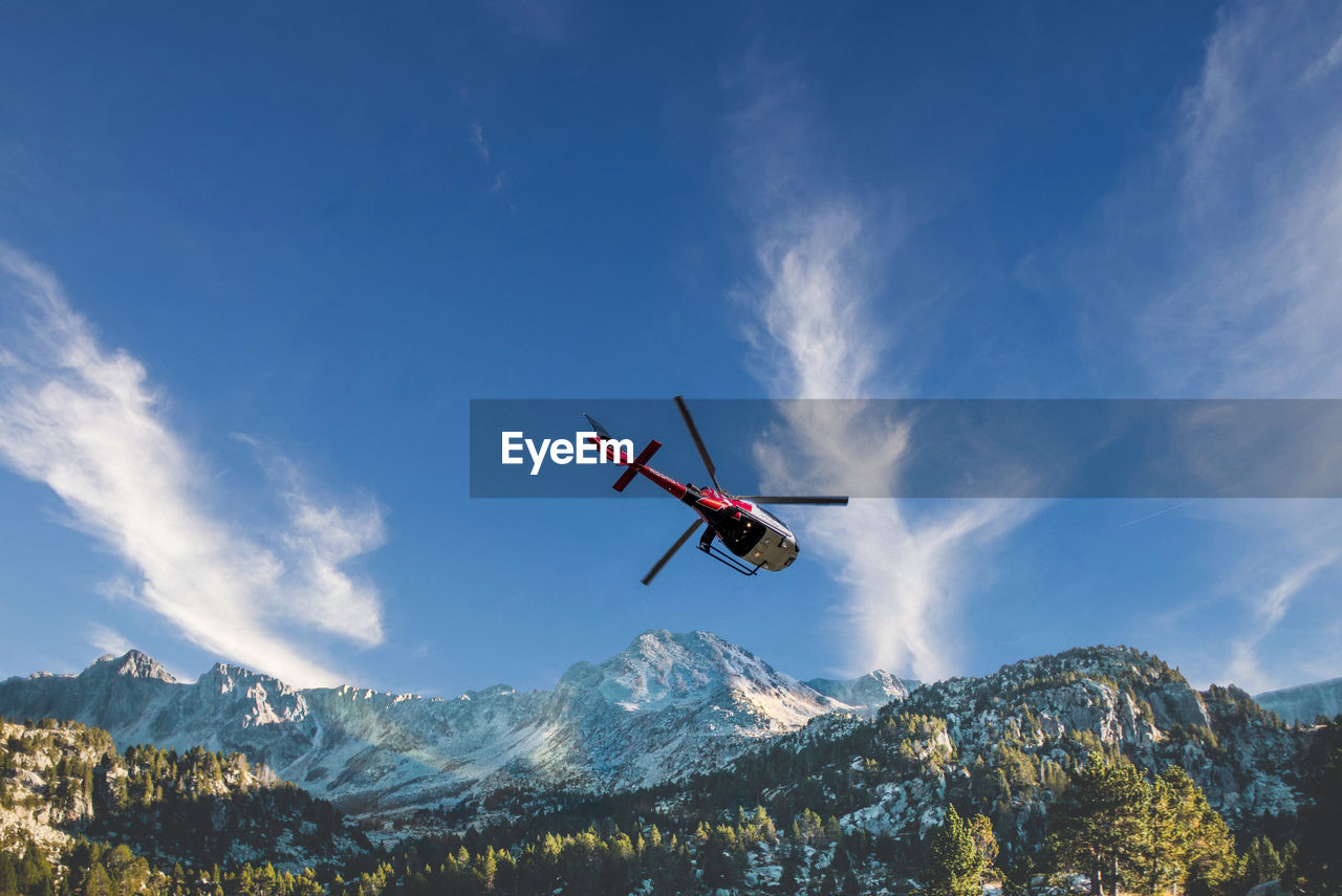 air vehicle, mountain, sky, flying, transportation, airplane, mountain range, nature, mode of transportation, cloud, helicopter, environment, mid-air, snow, motion, travel, skiing, scenics - nature, beauty in nature, landscape, blue, vehicle, day, tree, winter, aircraft, outdoors, forest, on the move, land, sports, cold temperature, travel destinations, extreme sports, low angle view