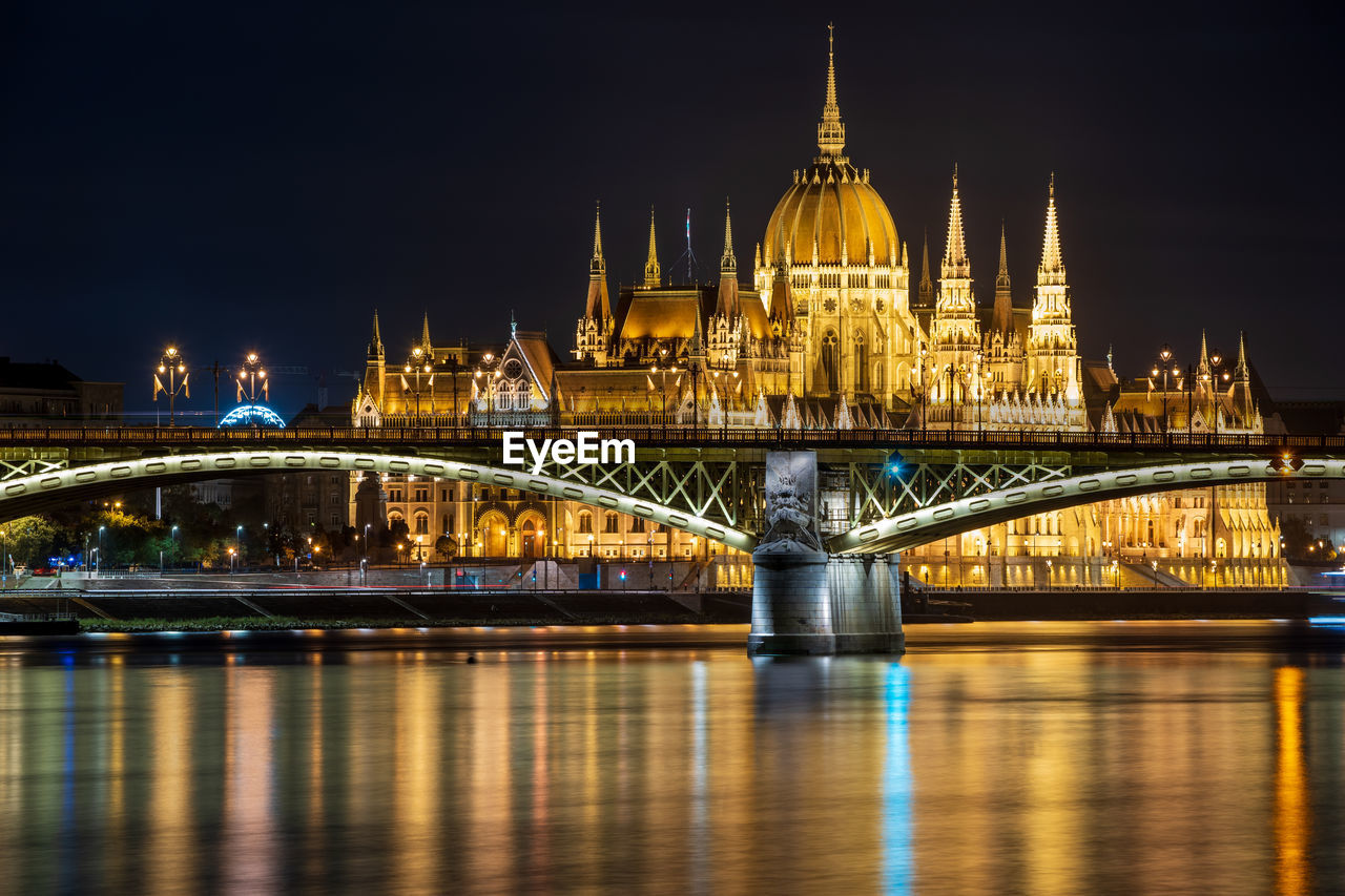 Illuminated bridge over river at night