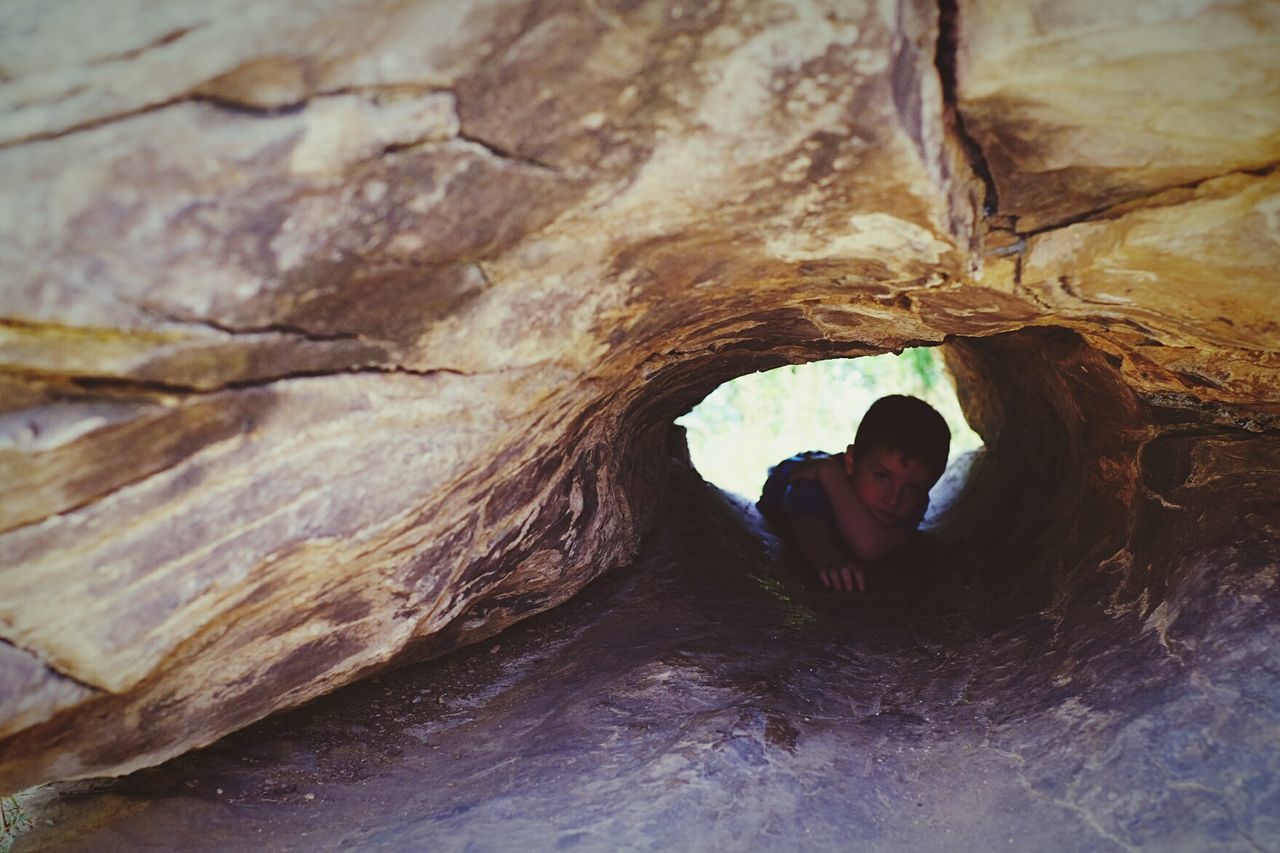 Portrait of boy seen through rock hole