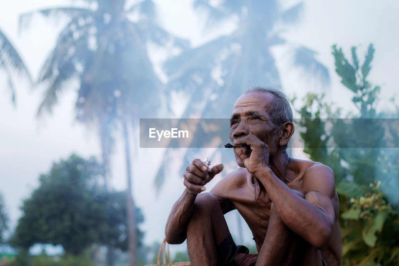 Old man are smoking in the countryside on field.