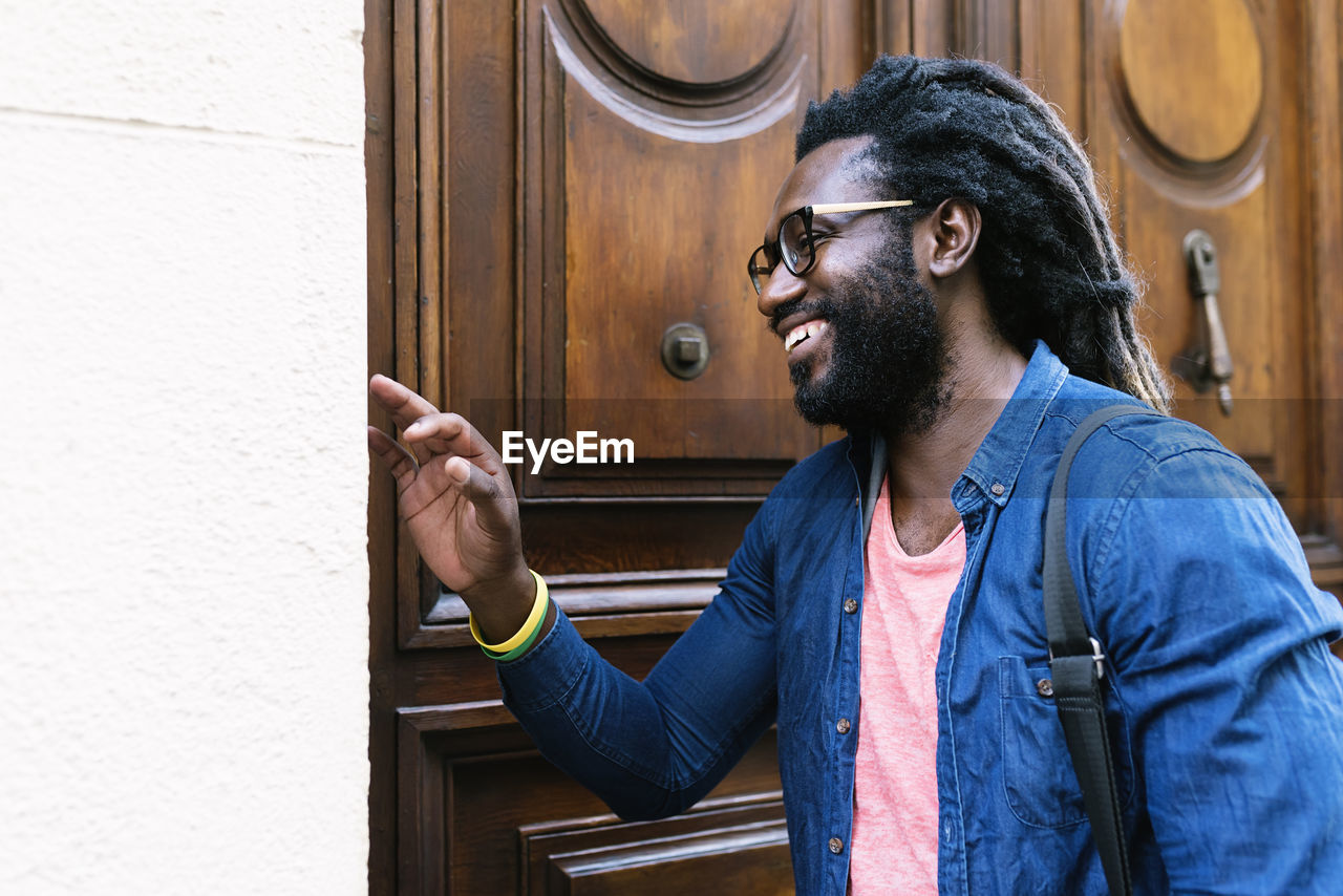 Cheerful young man standing by door in city