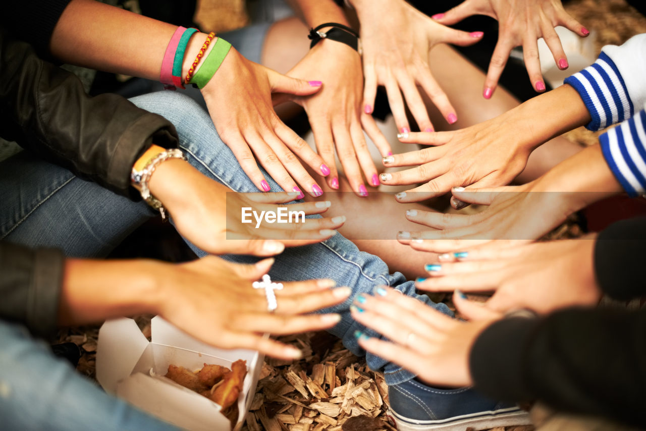 low section of friends stacking hands at home