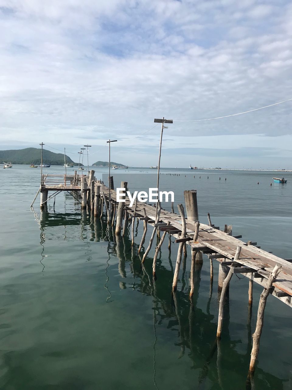 WOODEN POSTS IN SEA AGAINST SKY