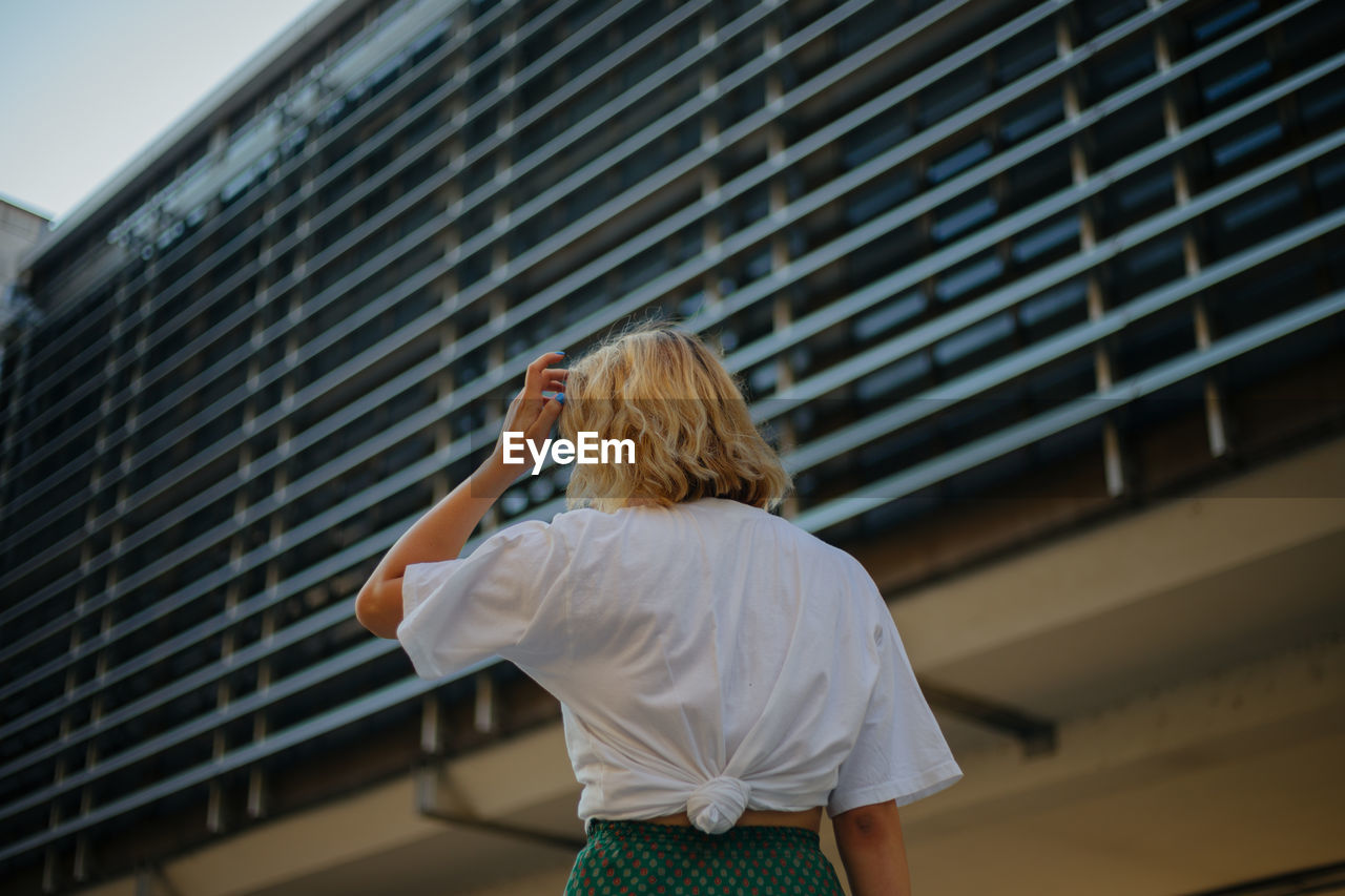 Rear view of woman standing against building