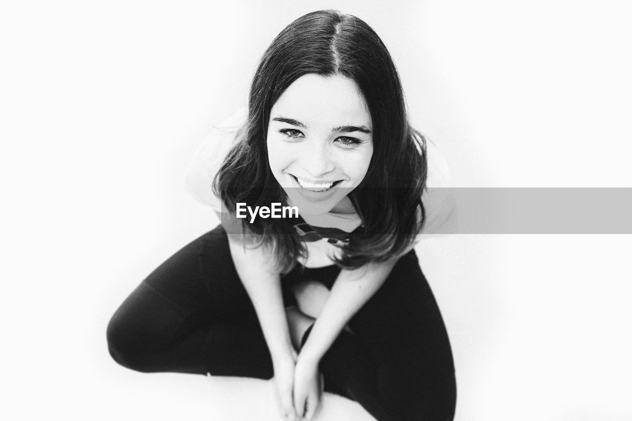 PORTRAIT OF SMILING WOMAN AGAINST WHITE BACKGROUND