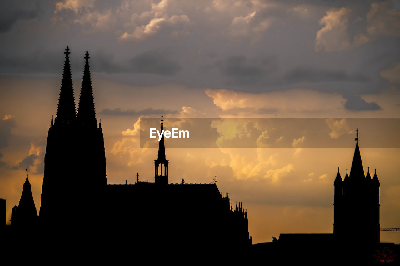 Silhouette cologne cathedral against cloudy sky at sunset