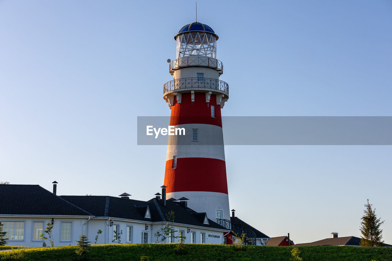 Lighthouse in red and white colors on the seashore, river bank or lake shore. lighthouse hotel.