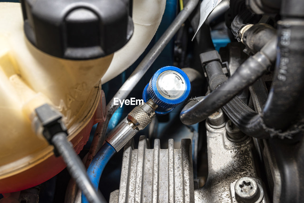 A blue quick-release coupler is installed on the valve from the air conditioning system in the car