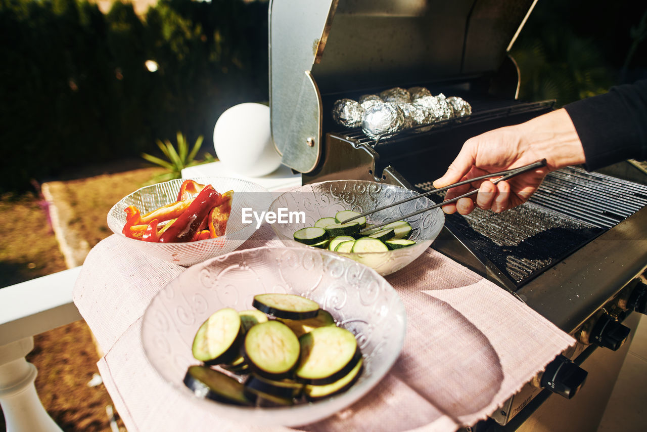 Cropped image of hand holding vegetable through serving tongs