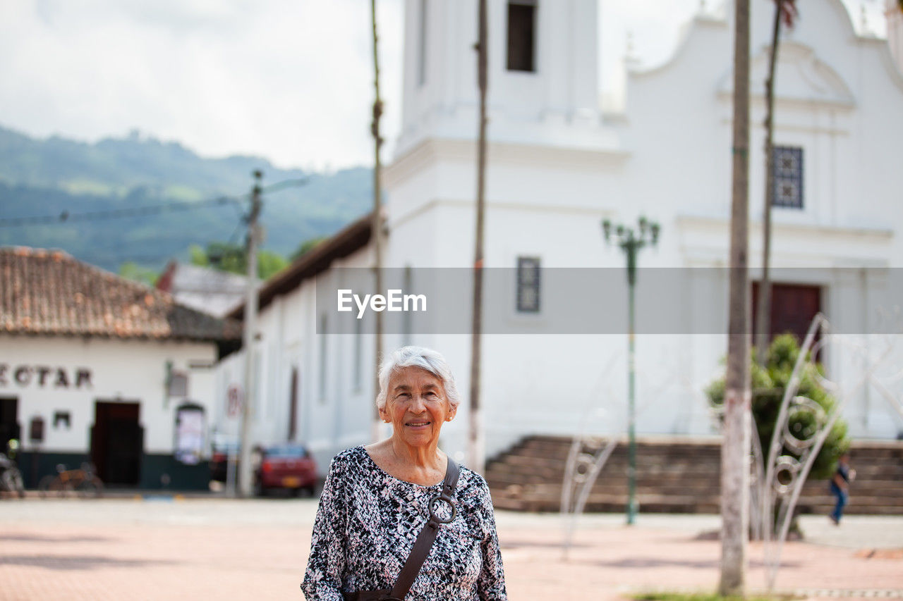 Senior adult woman at the central square in the city of guaduas. senior travel concept.