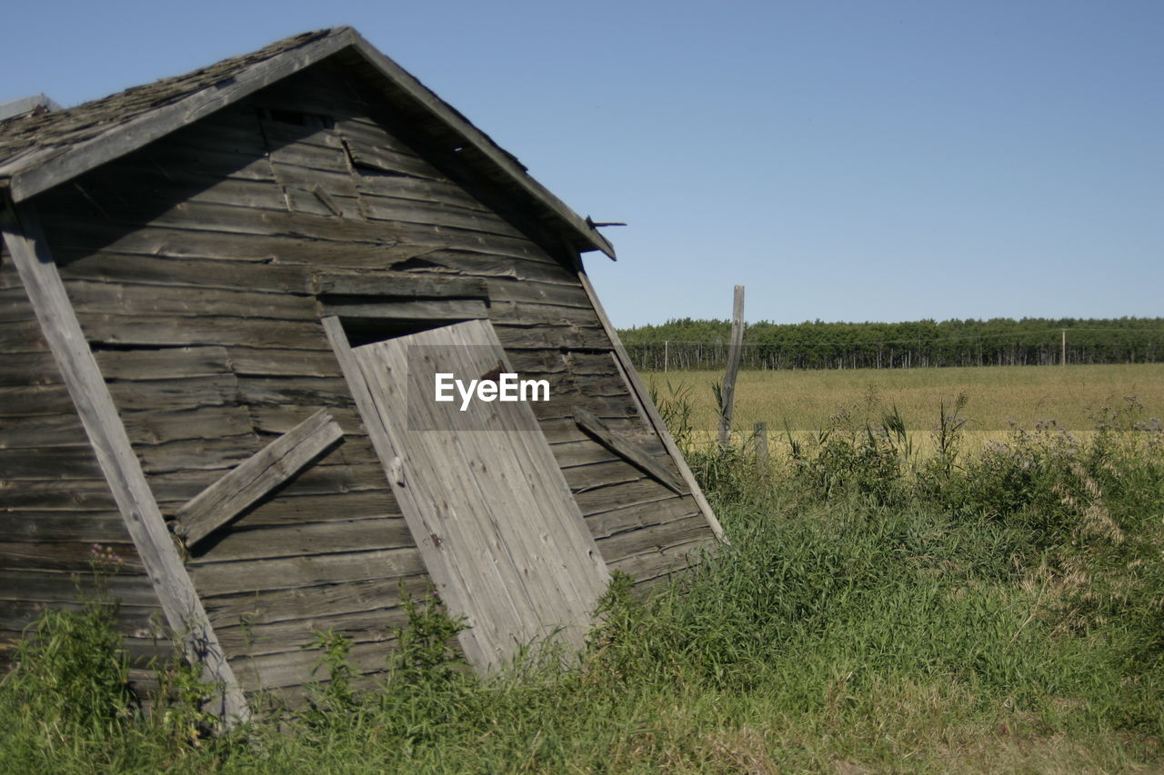 WOODEN STRUCTURE ON GRASSY FIELD AGAINST SKY