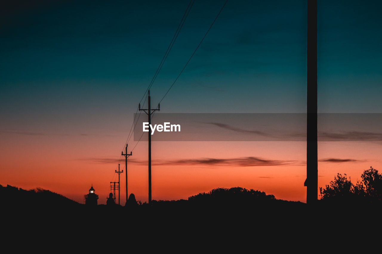 SILHOUETTE ELECTRICITY PYLON AGAINST ORANGE SKY