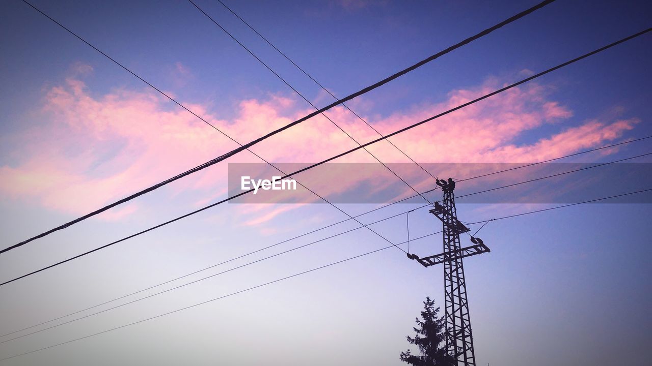 Low angle view silhouette of electricity pylon against sky during sunset