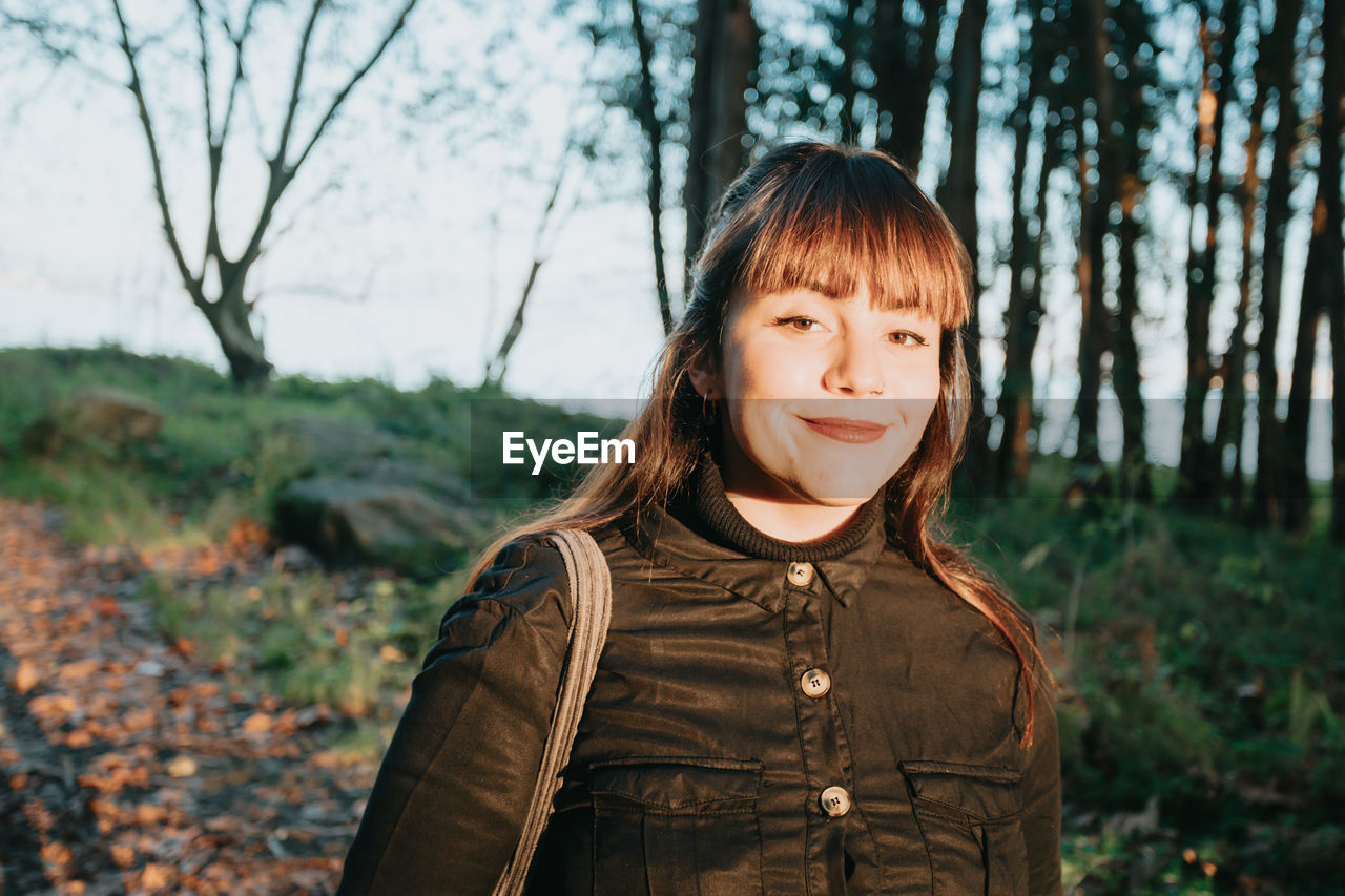 portrait of smiling young woman standing in forest