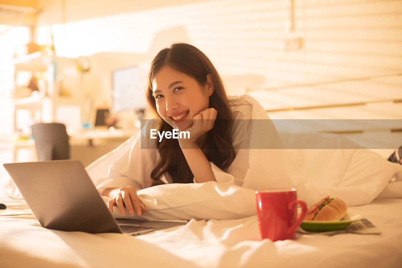 Woman working on bed in brightly lit bedroom