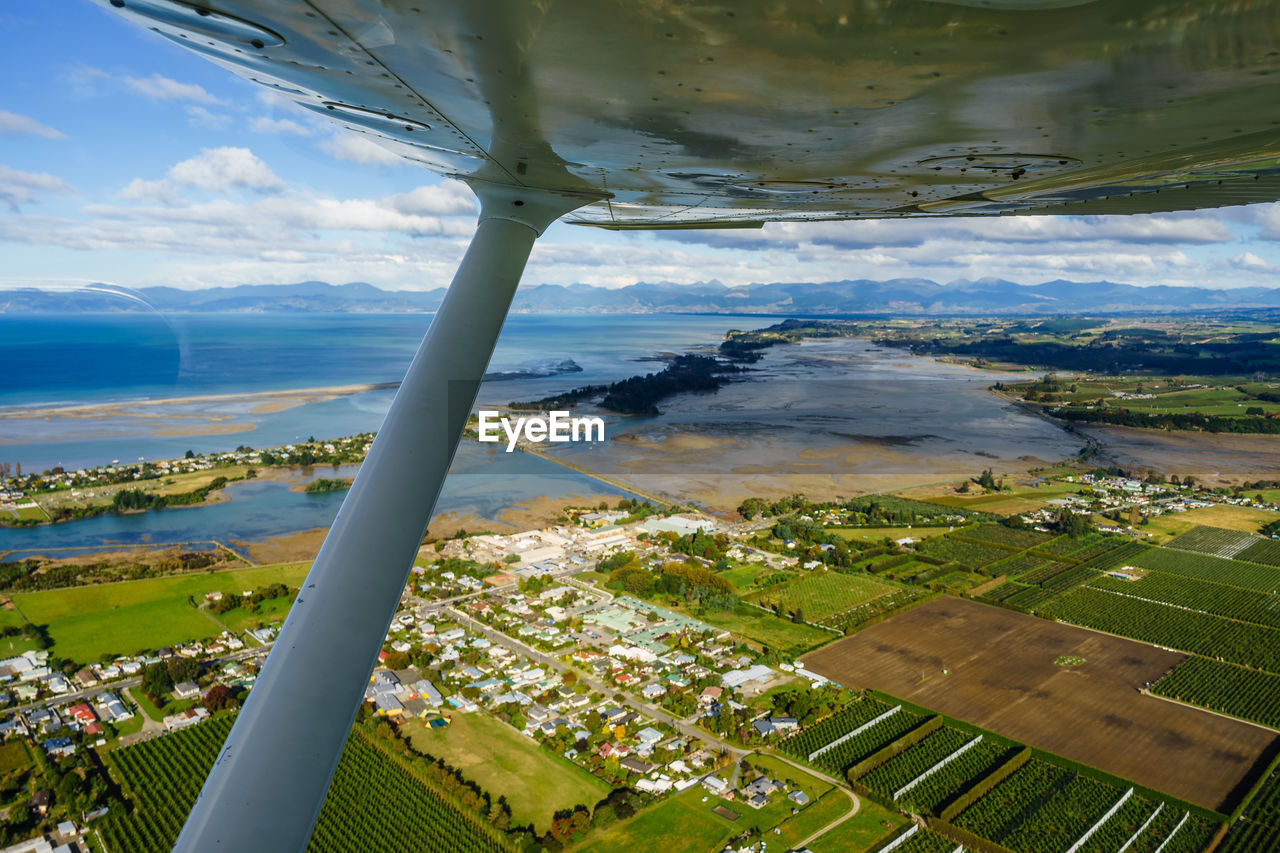 AERIAL VIEW OF LANDSCAPE AND SEA SEEN THROUGH AIRPLANE WINDOW