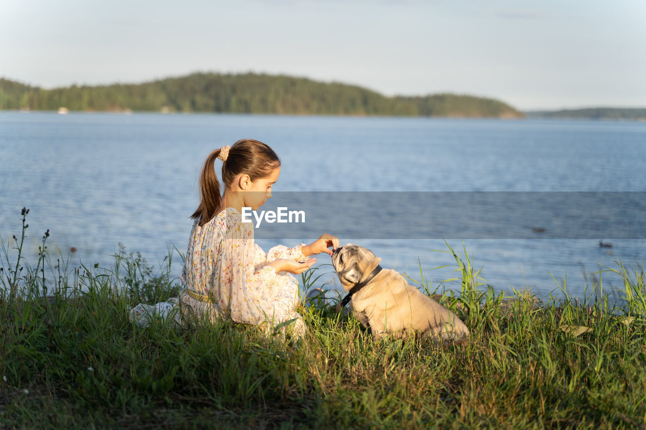 A girl and a pug on the lake shore