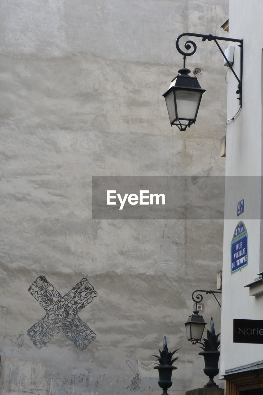 ILLUMINATED STREET LIGHT AGAINST WALL AND BUILDING