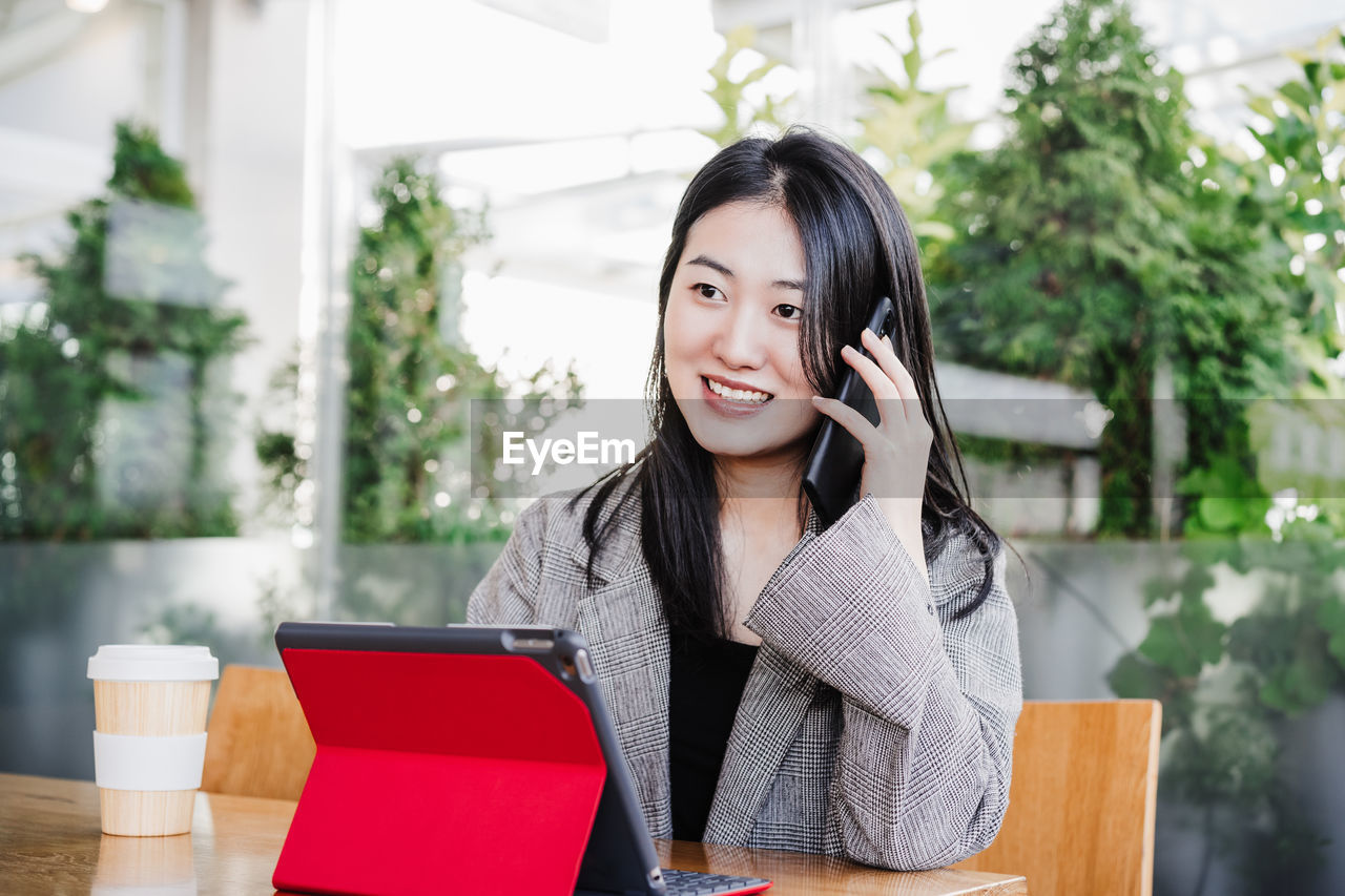 Professional chinese entrepreneur woman working on mobile phone in cafeteria. technology, lifestyle