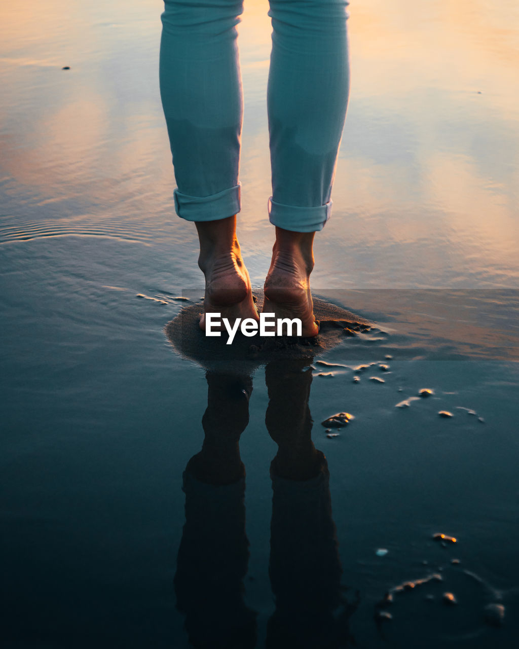 Low section of woman standing on lake against sky