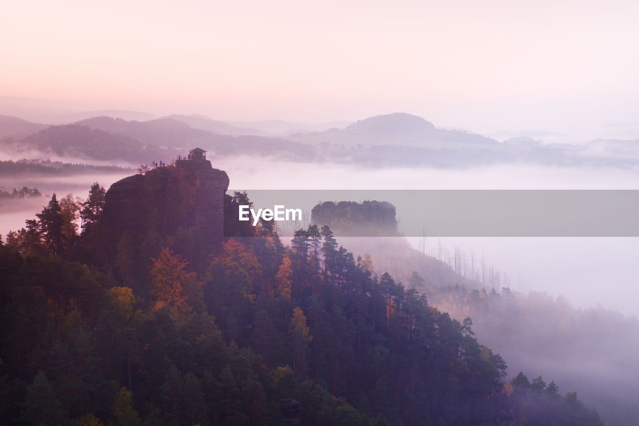 Cold misty daybreak in a fall valley of bohemian switzerland park. hill with hut on hill is magical 