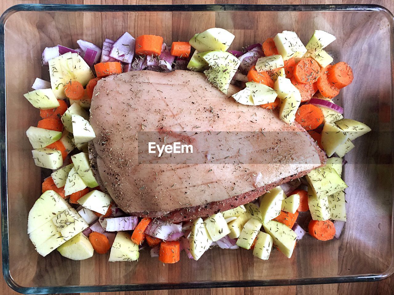 Directly above shot of roast pork and salad in glass bowl on table